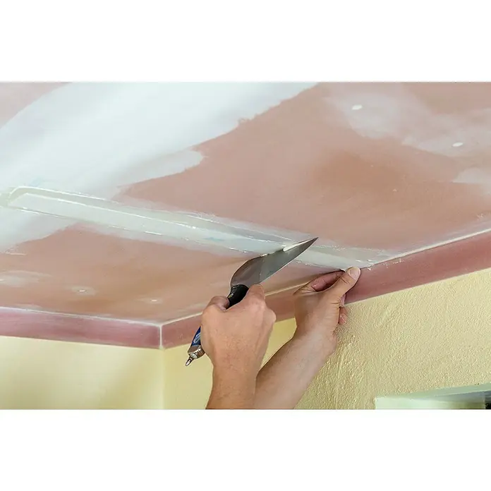 Knauf Fugenspachtel Leicht - 5 kg - Eine Person verwendet eine Spachtel, um Spachtelmasse auf eine Gipskartondecke aufzutragen, um eine glatte Oberfläche zu schaffen.