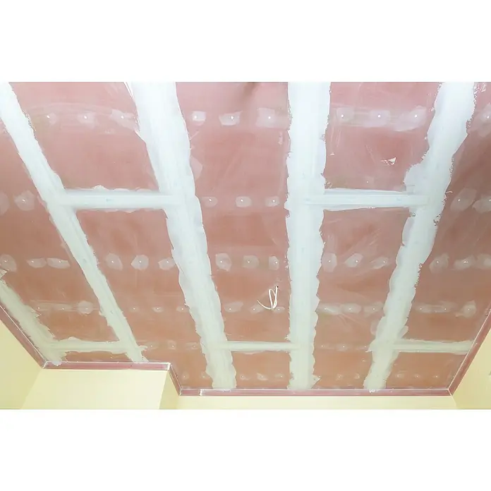 Knauf Fugenspachtel Leicht - 10 kg - Das Bild zeigt eine Decke im Bauzustand mit freiliegender rosa Gipskartonplatte, weißen Spachtelstreifen und hervorstehenden Kabeln, die eine unfertige Installation zeigt.