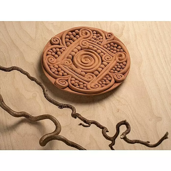 Glorex Hobby Time Softton - 2.500 g, Terracotta - Terrakotta-Tonrelief mit verschlungenen Spiral- und Punktmustern, auf hellem Holz neben gewundenen Ästen platziert.