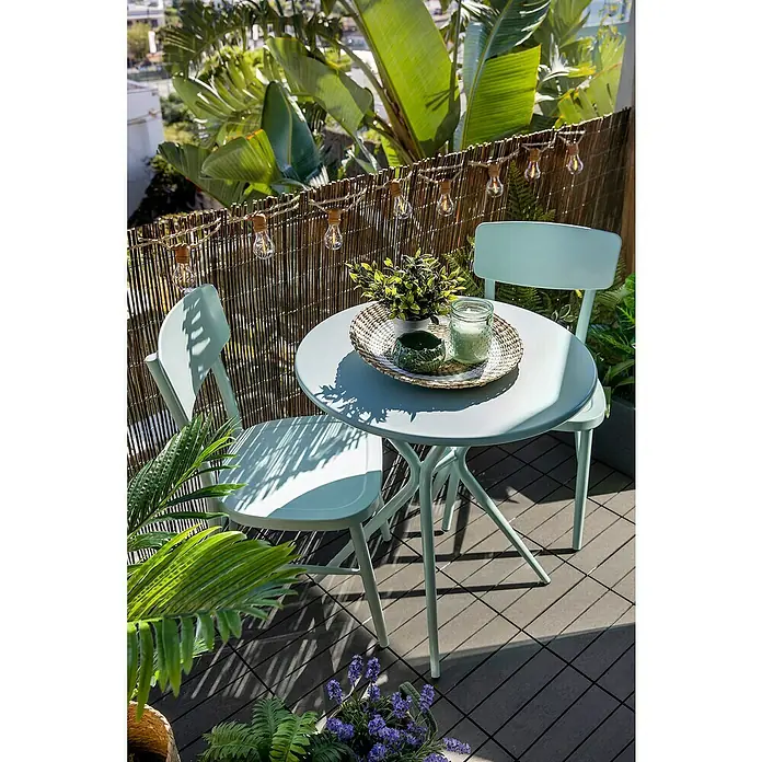 Mesa auxiliar de jardín Abigail - Aluminio, Verde - Una mesa azul con dos sillas en un balcón, decorada con plantas y luces, crea un ambiente relajante y acogedor.