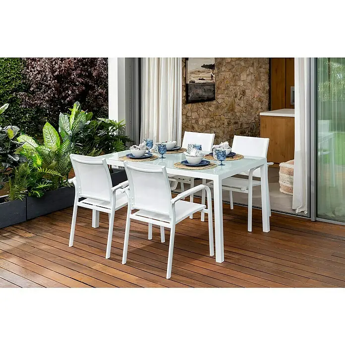 Sunfun Maja Sillón de jardín Maja - An x Pr x Al: 59,5 x 59 x 88 cm, Blanco, Aluminio/Textiline - Un juego de mesa de patio blanco con sillas y manteles individuales en una terraza de madera, rodeado de plantas, ideal para comer al aire libre.