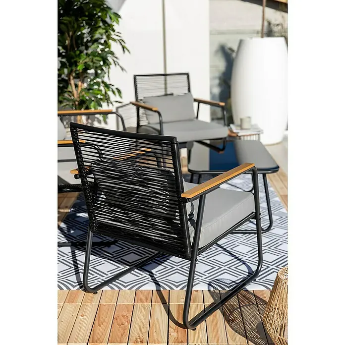 Sunfun Conjunto de muebles Susana - 4 pzs., Acero/Polywood, Negro - Primer plano de un elegante sillón negro con reposabrazos de madera y cojines grises colocado sobre una alfombra estampada, ideal para exteriores.