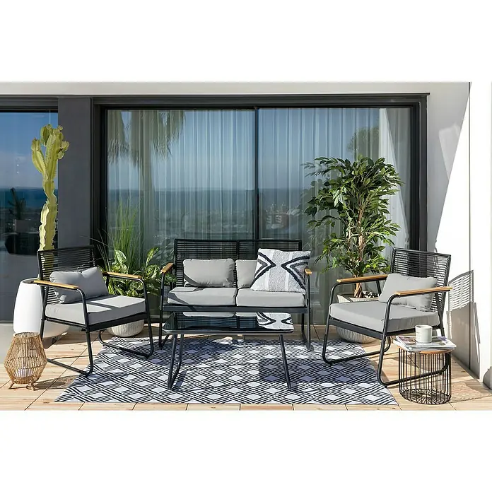 Sunfun Conjunto de muebles Susana - 4 pzs., Acero/Polywood, Negro - Un conjunto de patio con un sofá negro, dos sillas, una mesa y una alfombra geométrica. Plantas y cestas decorativas completan el ambiente.