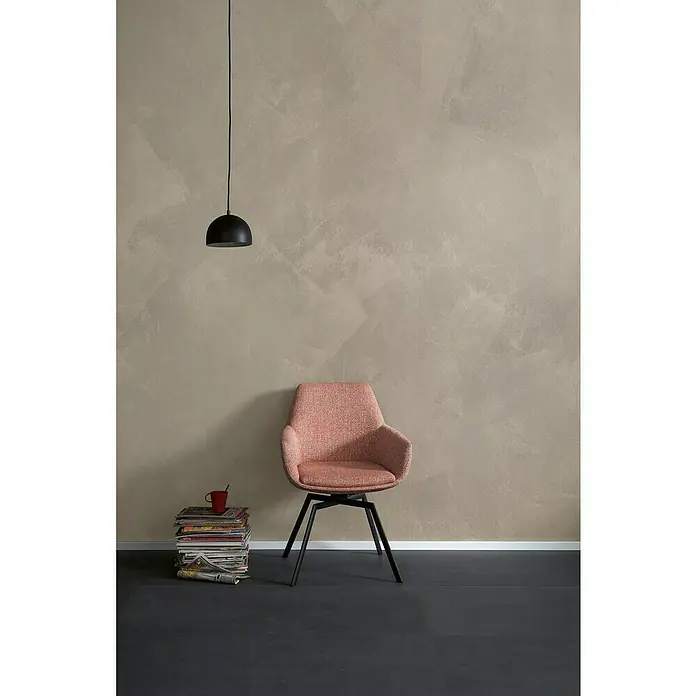 SCHÖNER WOHNEN-Farbe Trendstruktur Dekoputz-Set Stone-Optik - 6 -tlg., Kalkstein - Einrichtungsszene mit einem korallenroten Stuhl, einer Hängelampe und einem Stapel Zeitschriften vor einer strukturierten Wand, die eine gemütliche Atmosphäre schafft.
