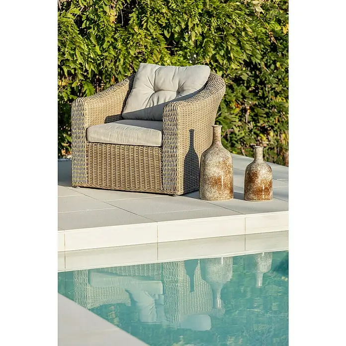 Sunfun Conjunto de muebles Belinda II - 4 pzs., Aluminio/Ratán sintético, Arena - Un primer plano de una butaca de ratán con cojines color crema de pie junto a dos jarrones decorativos, cerca de la piscina.