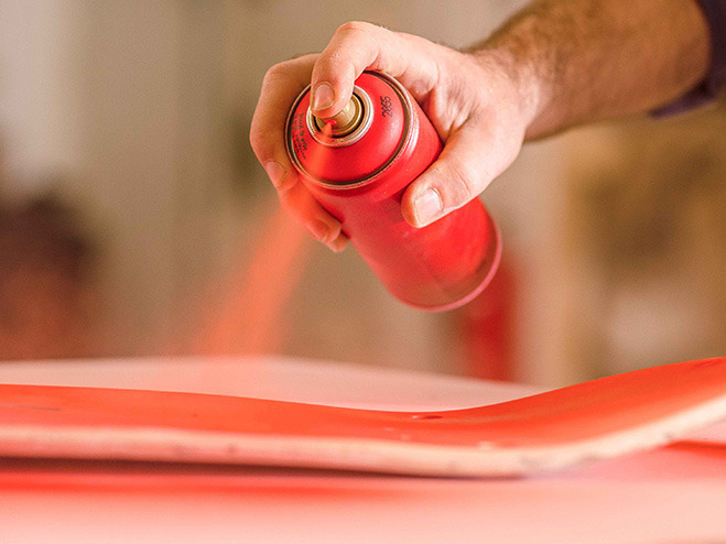 Das Skateboard wird mit rotem Sprühlack eingefärbt
