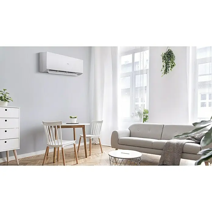 Haier Aire acondicionado Inverter Expert - 5.000 W, 5.650 W, 40 m², Blanco - Aire acondicionado blanco Haier montado en una pared luminosa sobre una mesa de comedor en un salón moderno.