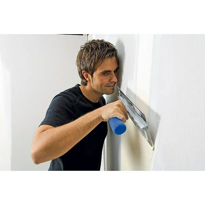 Knauf Fugenspachtel Uniflott - 8 kg - Ein Mann glättet eine Wand mit einem Spachtel, um eine ebene Oberfläche zu erzielen. Das Werkzeug ist entscheidend für ein sauberes Ergebnis.