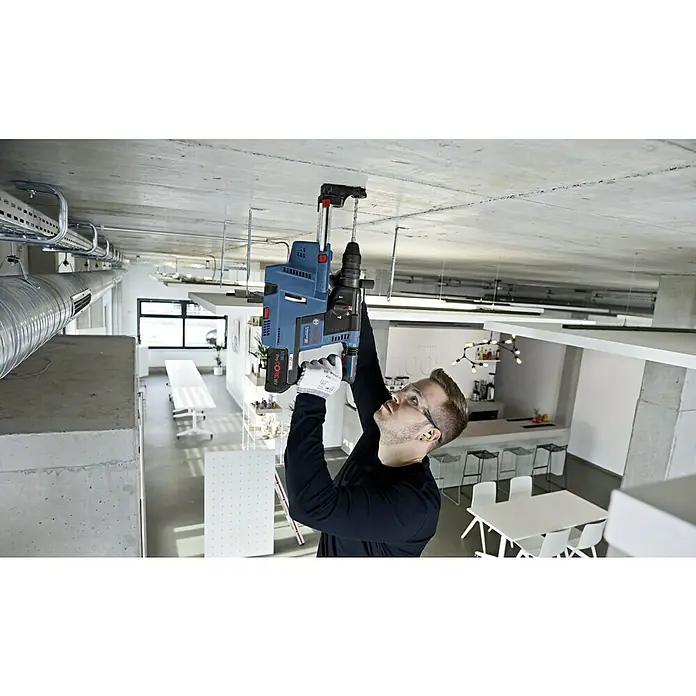 Bosch Professional AMPShare 18V Akku-Kombihammer GBH 18V-26 - 18 V, Ohne Akku, 2,6 J, L-Boxx - Ein Arbeiter bohrt mit einer blauen Bosch-Bohrmaschine ein Loch in eine Betondecke, wobei er Schutzbrille und Handschuhe trägt.