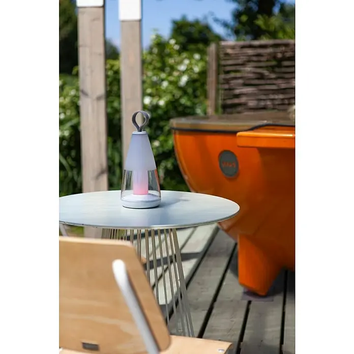 Lutec Akku-Tischleuchte PEPPER - 3 W, L x B x H: 12 x 12 x 29 cm, Weiß, RGBW - Nahaufnahme einer tragbaren Leuchte auf einem Tisch im Freien, die stimmungsvolles Licht erzeugt und eine gemütliche Atmosphäre schafft.