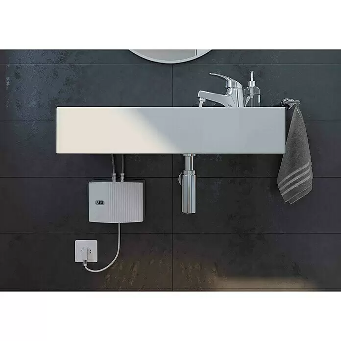 AEG Calentador de agua pequeño MTH 350 - 3,5 kW, Hidráulica, Abierto - Lavabo rectangular blanco con grifo cromado, dispensador de jabón y toalla gris. Debajo, un calentador de agua AEG conectado a un enchufe.