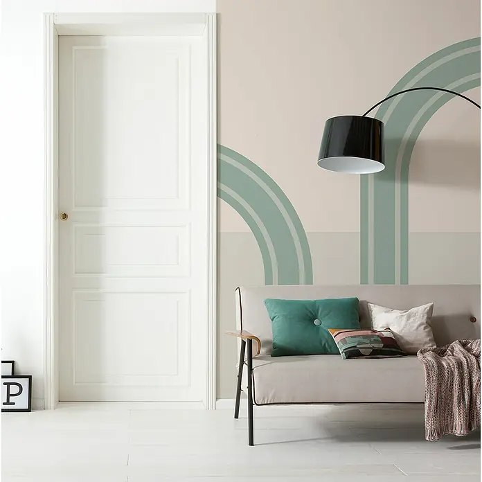 Komar Infinity 2 Fototapete Loop - B x H: 200 x 250 cm, Vlies - Einladendes Wohnzimmer mit einem stilvollen grauen Sofa, dekoriert mit Kissen und einer Decke, unter einer modernen Bogenlampe.