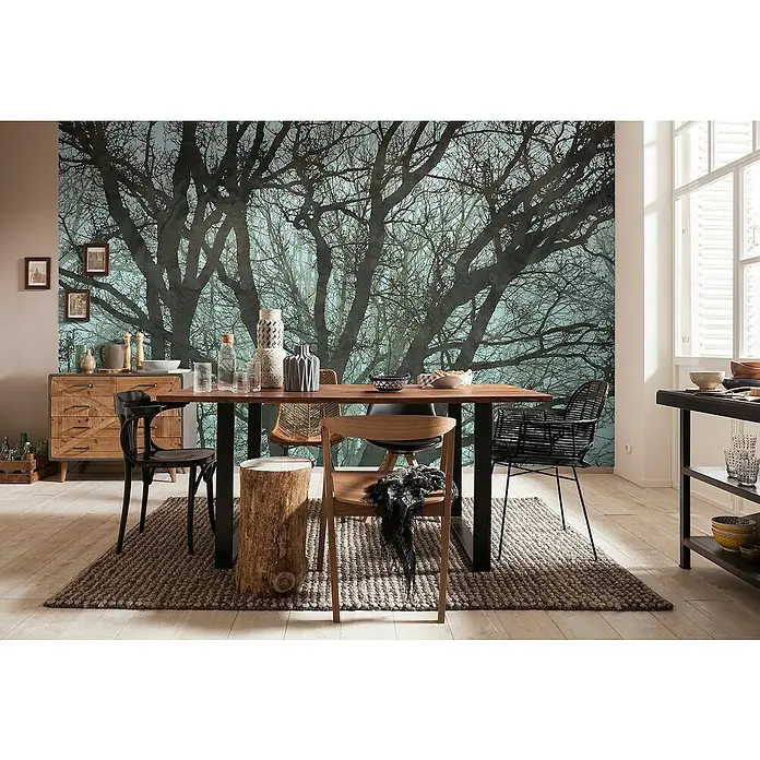 Komar Infinity 2 Fototapete Whispering Woods - Schwarz, B x H: 400 x 250 cm, Vlies - Esszimmer mit Holztisch, verschiedenen Stühlen auf einem Teppich, Kommode und Deko vor einer Waldtapete.
