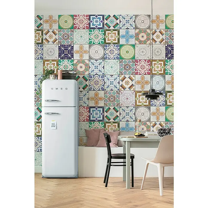 Komar Infinity 2 Fototapete Marrakech-MosaikB x H: 400 x 250 cm, Vlies - Eine Küche mit einem weißen Smeg Kühlschrank, einem hellgrünen Tisch und Stühlen vor einer bunten Fliesenwand.