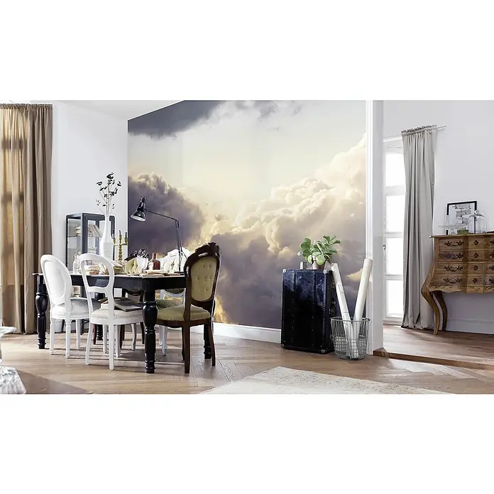 Komar Infinity 2 Fototapete Cloud Cast - B x H: 300 x 250 cm, Vlies - Esszimmer mit Esstisch und Stühlen vor einer Wandtapete mit Wolkenmotiv. Eine Kommode und ein Koffer ergänzen die Einrichtung.