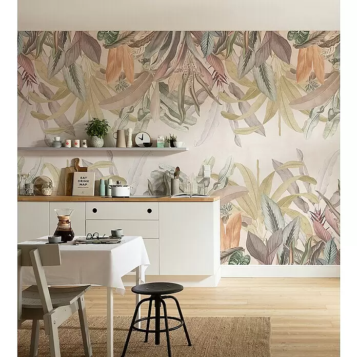 Komar Infinity 2 Fototapete Mirror Maison - B x H: 200 x 250 cm, Vlies - Botanische Tapete mit großen Blättern in Grün-, Braun-, Beige- und Rosatönen, die eine Küchenwand über weißen Schränken und einem Esstisch bedeckt.