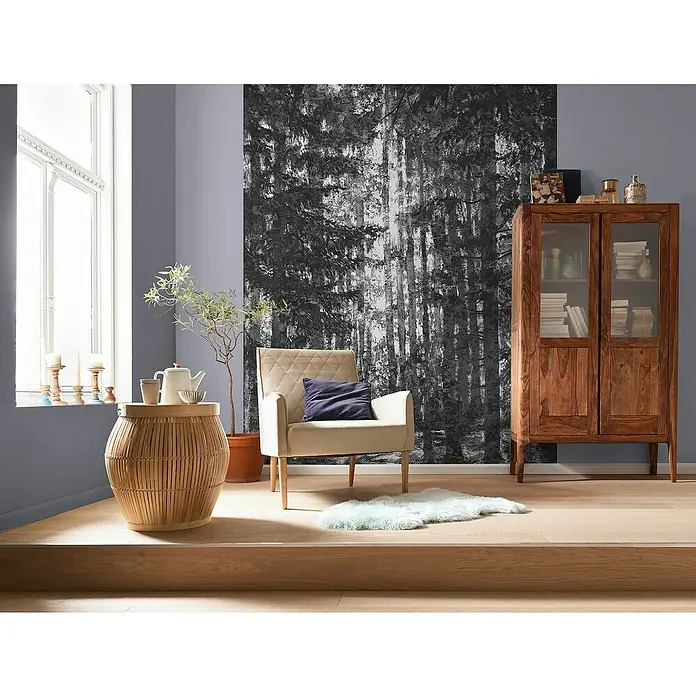Komar Infinity 2 Fototapete Lustres Lapland - B x H: 200 x 250 cm, Vlies - Einladendes Wohnzimmer mit einem beigen Sessel, einem Holztisch und einem Holzschrank vor einer Waldtapete.