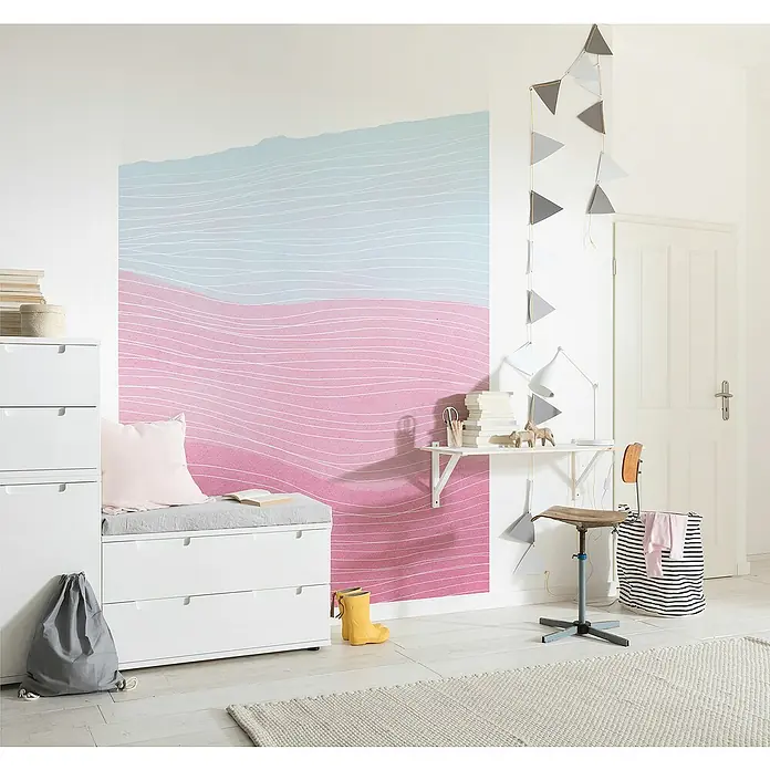 Komar Infinity 2 Fototapete Strawberry Streets - B x H: 200 x 250 cm, Vlies - Einladendes Kinderzimmer mit weißen Möbeln, darunter ein Schrank mit Sitzkissen und ein minimalistischer Schreibtisch. Die Wandgestaltung ist farbenfroh.