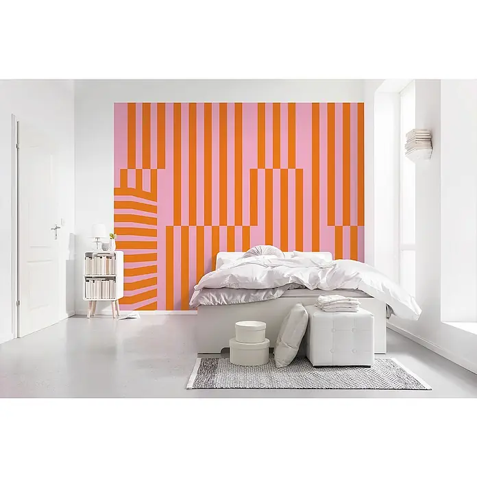 Komar Infinity 2 Fototapete Maximal MinimalismB x H: 300 x 250 cm, Vlies - Schlafzimmer mit auffälliger pink-orange gestreifter Tapete, weißem Bett und Nachttisch. Die Tapete ist der Blickfang in diesem modernen Raum.