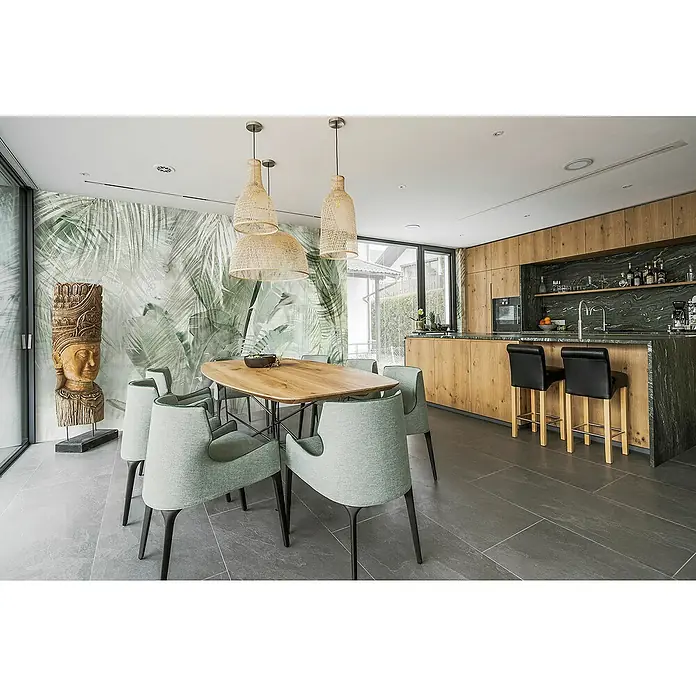 Komar Infinity 2 Fototapete Botanical Boho - B x H: 400 x 250 cm, Vlies - Moderne Esszimmergestaltung mit einem Holztisch, hellen Stühlen und Pendelleuchten über dem Tisch. Die Küche ist im Hintergrund sichtbar.