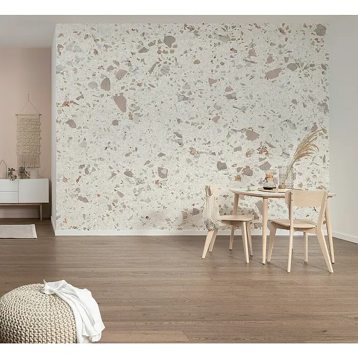 Komar Infinity 2 Fototapete Tasteful TerrazzoB x H: 400 x 250 cm, Vlies - Helles Esszimmer mit Terrazzo-Akzentwand. Der Raum verfügt über einen Holzboden, einen runden Tisch mit Stühlen und eine moderne Einrichtung.