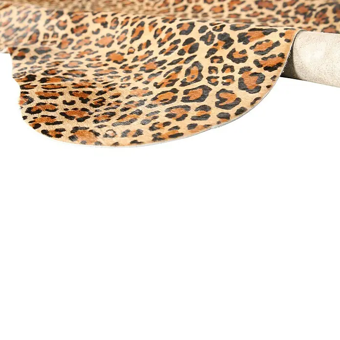 Esbeco Kuhfell - 100 % Echtfell, Leopard - Nahaufnahme eines Stoffes mit Leopardenmuster, der über eine Rolle gewickelt ist. Das Muster zeigt schwarze Rosetten auf beigem Grund.