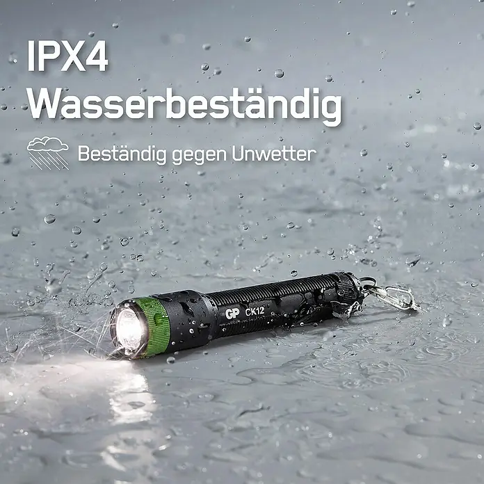 GP Taschenlampe CK12 - 20 lm, IPX4 - Schwarze GP CK12 Taschenlampe mit grünen Akzenten, die im Regen liegt und leuchtet. Wasserbeständig und zuverlässig.