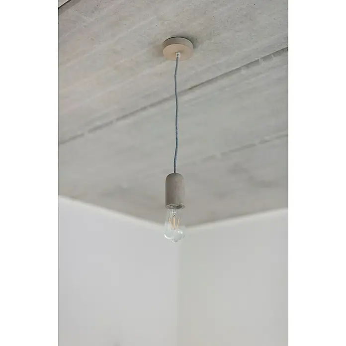 Chacon Casquillo de hormigón - Hormigón, Gris, 1 ud. - Lámpara colgante con base de hormigón y bombilla, colgando de un techo de hormigón, mostrando un diseño moderno y minimalista.