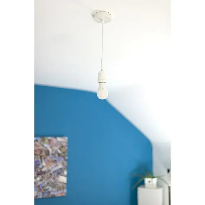 Chacon Casquillo cerámico - Cerámica, Blanco, 1 ud. - Primer plano de una bombilla blanca individual que cuelga de un soporte de techo blanco con un cable, con una decoración de pared colorida al fondo.