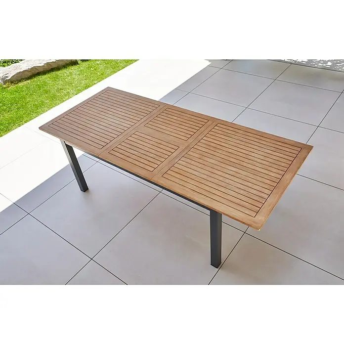 Sunfun Gartenmöbel-Set Carina/Maja - 7 -tlg., Akazie/Textilen/Metall, Naturbraun/Anthrazit, Gartenstuhl klappbar - Bild einer rechteckigen Holzterrassentisch mit dunklen Beinen auf einer gefliesten Terrasse im Freien.
