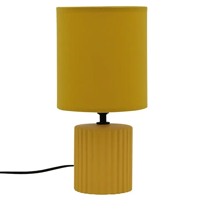 Idp Lampshades Lámpara de sobremesa Colonia - 40 W, L x An x Al: 15 x 15 x 30 cm, Mostaza, E14 - Primer plano de una moderna lámpara de mesa de color amarillo mostaza con base acanalada y pantalla cilíndrica sobre un fondo negro.