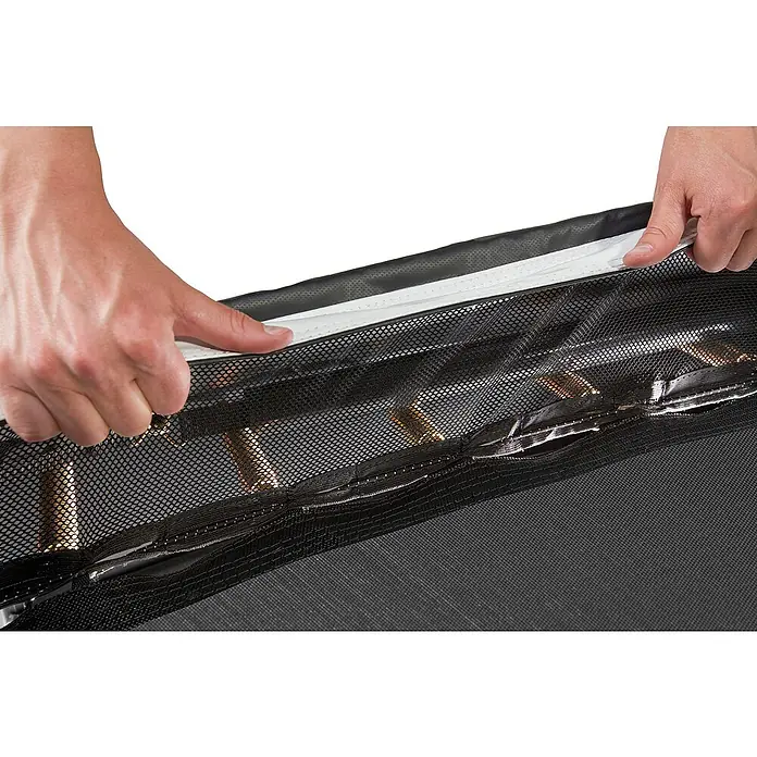 Salta Trampolin Royal Baseground305 x 214 cm, Schwarz - Detailaufnahme einer Hand, die einen Reißverschluss an einem schwarzen Netzgewebe öffnet. Der Fokus liegt auf der Funktionalität und Beschaffenheit des Produkts.