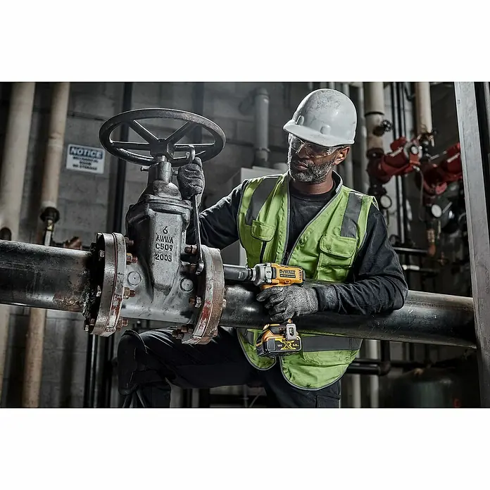 DeWalt XR 18V Llave de impacto de batería DCF891NT - 18 V, Sin batería, 1.084 Nm - Un trabajador opera una llave de impacto inalámbrica DeWalt en una gran válvula montada en una tubería.