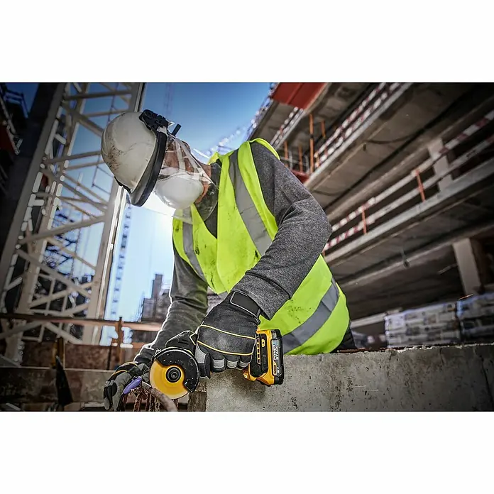 DeWalt XR 18V Amoladora angular de batería DCS438N - 18 V, Sin batería - Un trabajador de la construcción usa una amoladora angular DeWalt en una obra, usando equipo de seguridad y guantes.