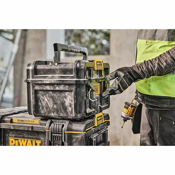 DeWalt Cargador de baterías Toughsystem - L x An x Al: 14 x 38 x 23 cm - Primer plano de cajas de herramientas DeWalt ToughSystem 2.0 apiladas en una obra en construcción, manipuladas por una persona.