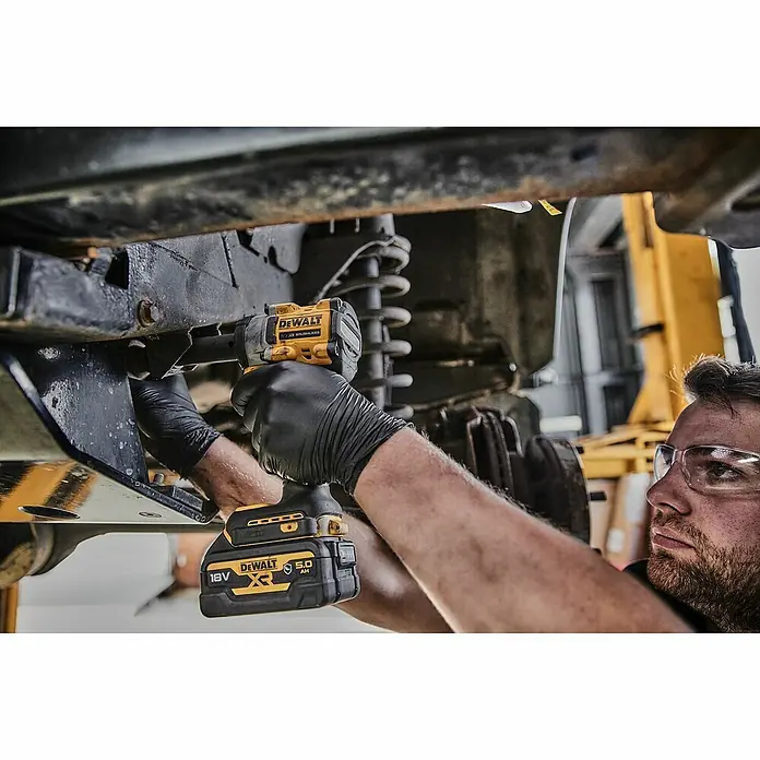 DeWalt XR 18V Llave de impacto de batería DCF921N - 18 V, Sin batería, 610 Nm - Un hombre usa una llave de impacto inalámbrica DeWalt con una batería XR 18V 5.0 Ah para trabajar en un vehículo.