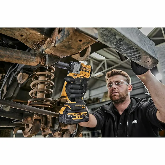 DeWalt XR 18V Akku-Schlagschrauber DCF921N-XJ - 18 V, Ohne Akku, 610 Nm - Ein Mechaniker benutzt einen gelb-schwarzen DeWalt Akku-Schlagschrauber mit 18V-Akku unter einem Auto.