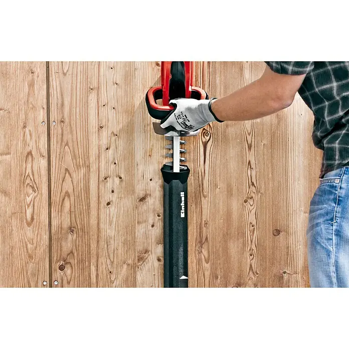 Einhell Power X-Change 18V Akku-Heckenschere GC-CH 1855/1 Li-Solo - 18 V, Ohne Akku, Schnittlänge: 55 cm - Die Einhell Akku-Heckenschere mit Schutzhülle wird an einer Holzwand gehalten. Das Produkt ist sicher und einsatzbereit für den nächsten Einsatz.