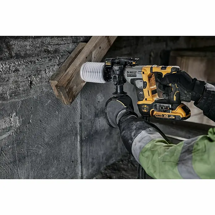 DeWalt XR 18V Martillo combinado de batería DCH172NT - 18 V, Sin batería, 1,4 J - Primer plano de un martillo perforador DeWalt amarillo y negro con extracción de polvo perforando una pared de hormigón con soporte de madera.