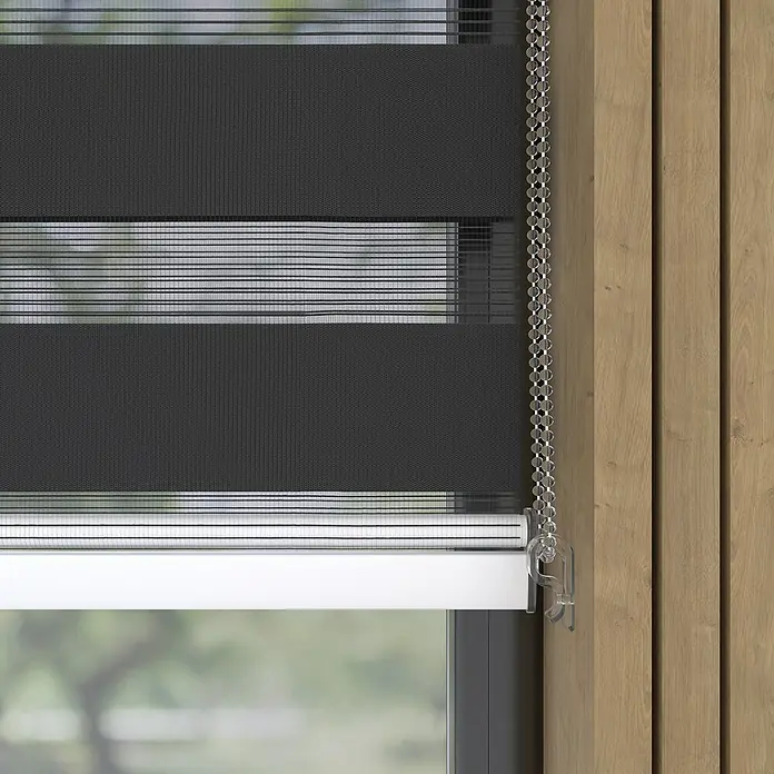 Expo Ambiente Doppelrollo mit KassetteB x H: 200 x 175 cm, Schwarz, Tageslichtdurchlässig - Nahaufnahme einer grauen Doppelrollo-Fensterabdeckung mit Kettenzug und transparenten Streifen für variable Lichtsteuerung.