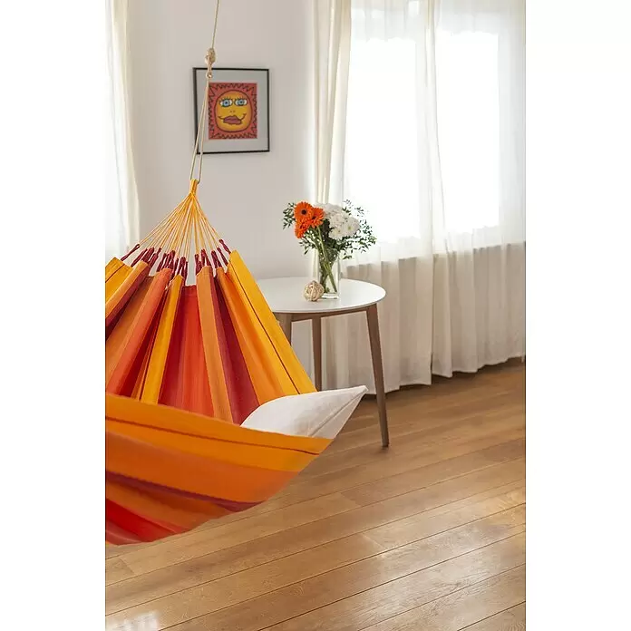 La Siesta Hängematte Modesta - L x B: 300 x 140 cm, Volcano, Single - Ein orange-rot gestreifter Hängesessel mit weißem Kissen hängt in einem sonnigen Raum.