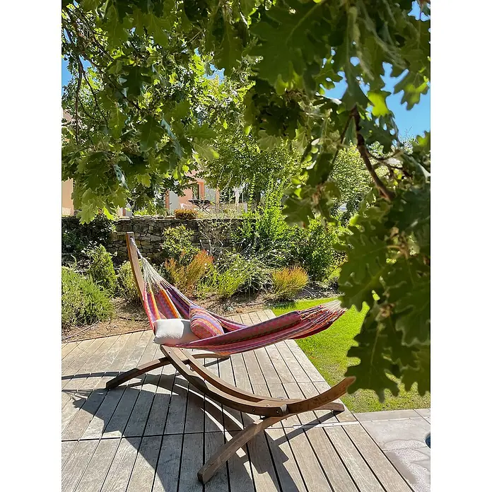 La Siesta Doppelhängematte Flora - L x B: 350 x 160 cm, Flowers, Ausführungseigenschaft: Double - Entspannen Sie im Freien in einer farbenfrohen Hängematte auf einem Holzgestell, umgeben von üppigem Grün und sanftem Sonnenlicht.