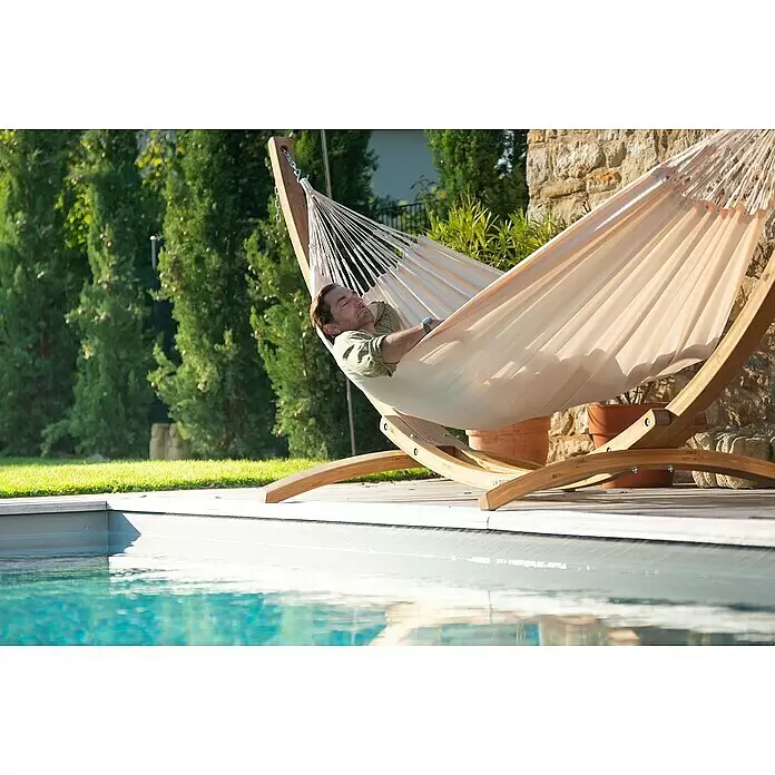 La Siesta Hängematte Brisa Kingsize - L x B: 400 x 180 cm, Vanilla - Mann entspannt in einer beigen Hängematte mit Holzgestell neben einem Swimmingpool.