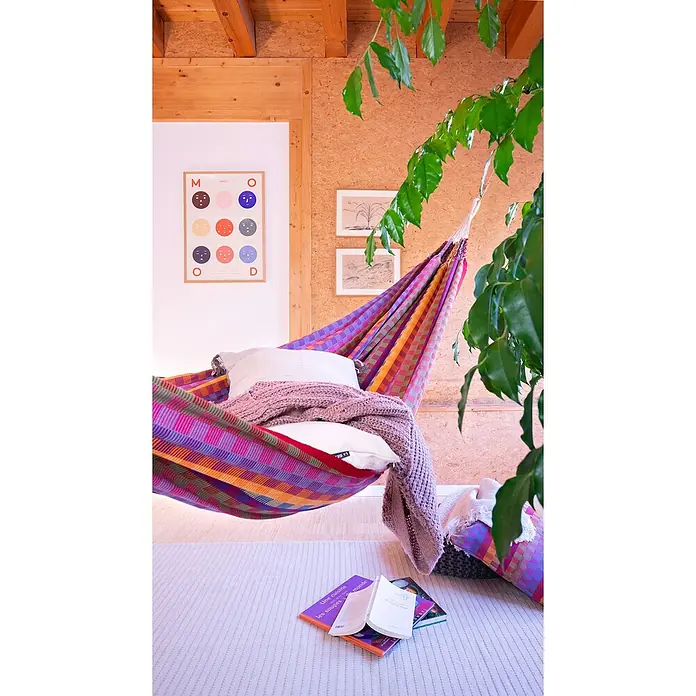 La Siesta Doppelhängematte Flora - L x B: 350 x 160 cm, Flowers, Ausführungseigenschaft: Double - Bunte Hängematte mit Kissen und Decke, einladend zum Entspannen mit Büchern auf einem hellen Teppich und Zimmerpflanze im Raum.