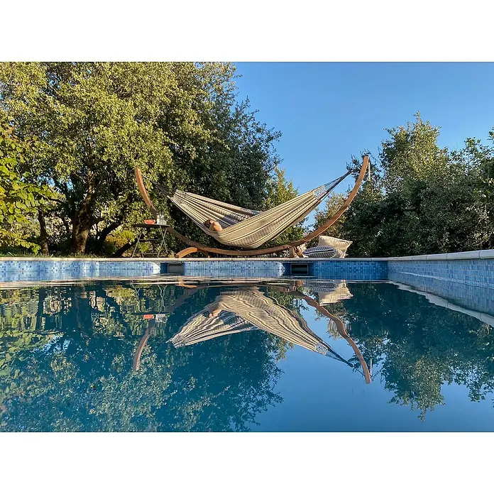 La Siesta Doppelhängematte Flora - L x B: 350 x 160 cm, Zebra, Ausführungseigenschaft: Double - Eine Hängematte am Pool, die zum Entspannen einlädt. Die ruhige Wasseroberfläche spiegelt die Hängematte und die Umgebung wider.