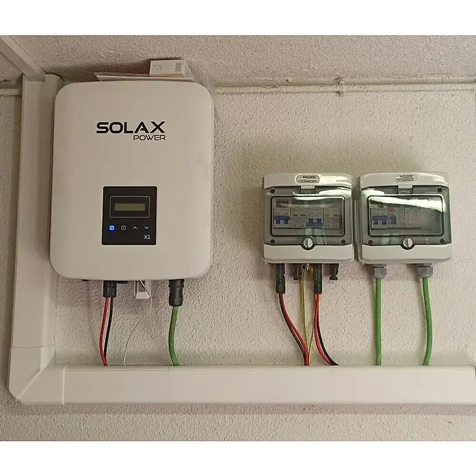 Inversor X1 Boost - 5 kW, L x An x Al: 14,3 x 43 x 34,15 cm - Primer plano de un inversor Solax Power X1 y dos cajas de fusibles Noark montadas en la pared.