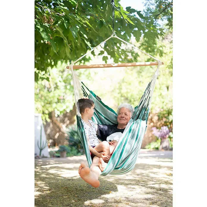 La Siesta Hängesessel Habana Comfort - L x B x H: 180 x 115 x 160 cm, Agave - Ein entspanntes Bild von Großvater und Enkel in einer gestreiften Hängematte im Garten, umgeben von üppigem Grün.