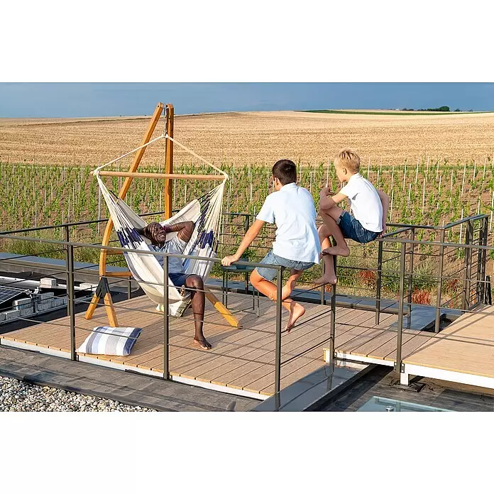 La Siesta Hängesessel Domingo Kingsize - L x B x H: 210 x 130 x 170 cm, Sea Salt - Mann entspannt in gestreiftem Hängesessel auf einer Terrasse mit Blick auf einen Weinberg, mit zwei Jungen am Geländer.