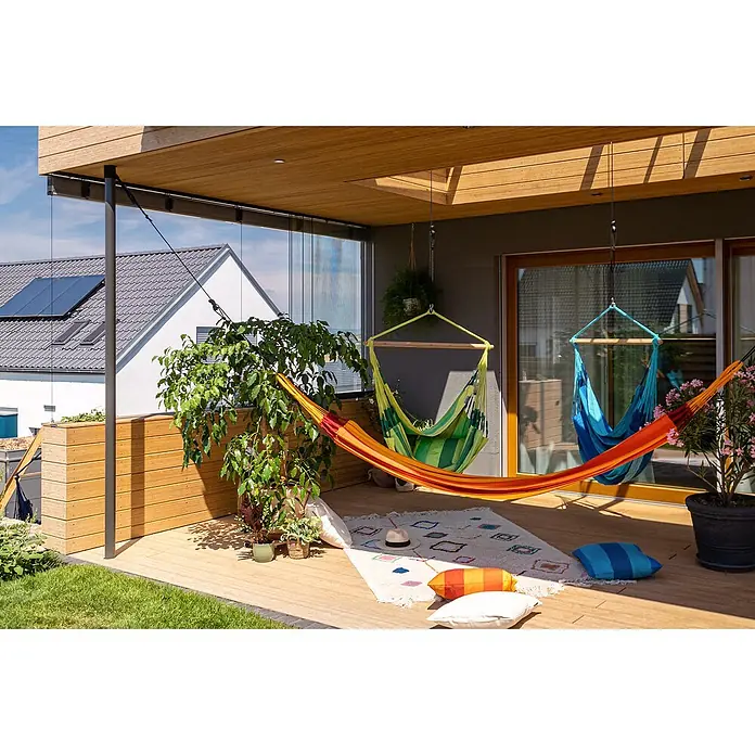 La Siesta Hängematte Modesta - L x B: 350 x 160 cm, Volcano, Double - Einladende Terrasse mit Hängematten in leuchtenden Farben, die zum Entspannen einladen. Pflanzen und Kissen sorgen für Gemütlichkeit.