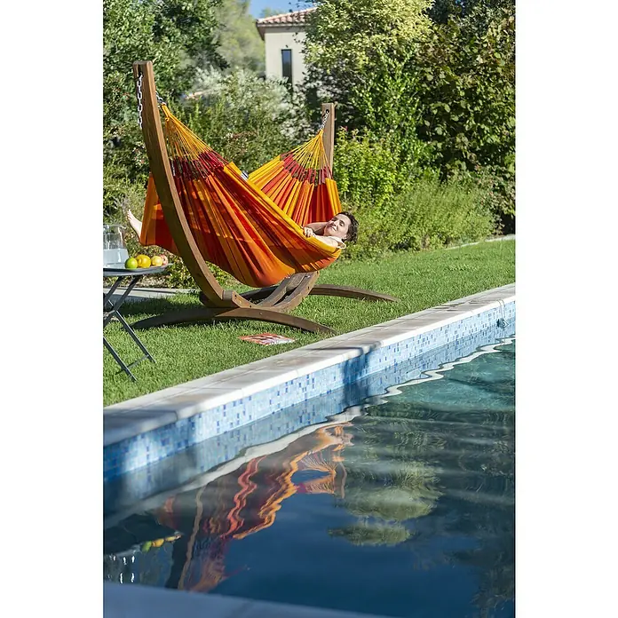 La Siesta Hängematte Modesta - L x B: 350 x 160 cm, Volcano, Double - Frau entspannt in einer farbenfrohen Hängematte mit Holzgestell im Garten neben einem Pool. Entspannung pur im Freien.